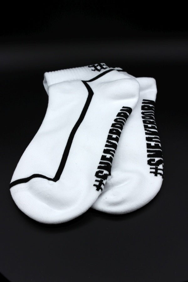 Ein Paar Sk8erboy® #SNEAKERPORN Socken schwarz, mit schwarzem Stoff und auffälligem Sk8erboy® Branding an den Seiten, auf einem schlichten schwarzen Hintergrund.